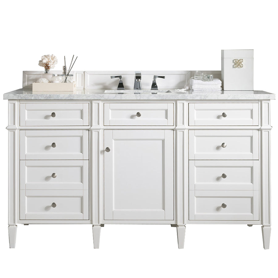 A white bathroom vanity with a marble countertop, double faucets, multiple drawers, and a central cabinet. Decorative items and toiletries are neatly arranged on the countertop.