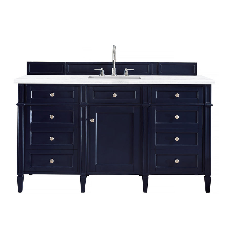 A navy blue bathroom vanity with a white countertop, central sink, silver faucet, and multiple drawers and a cabinet door beneath.