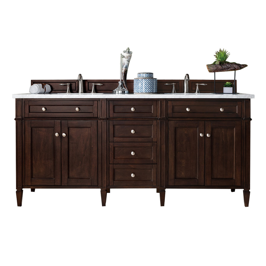 Double-sink bathroom vanity with dark wood cabinetry, a white countertop, and silver hardware. Decorative items including a vase, plant, rolled towels, and a blue-and-white jar sit on the back ledge.
