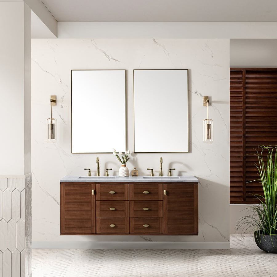 A modern bathroom features a wooden double-sink vanity with brass fixtures, two rectangular mirrors, wall-mounted lights, a marble backsplash, and a potted plant on the right.
