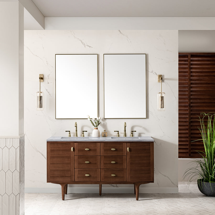 The Amberly 60" Double Bowl Vanity features a walnut wood cabinet, double sinks, brass fixtures, and two rectangular mirrors against a white marble wall. Wall sconces and a potted plant complete this stylish mid-century modern look.
