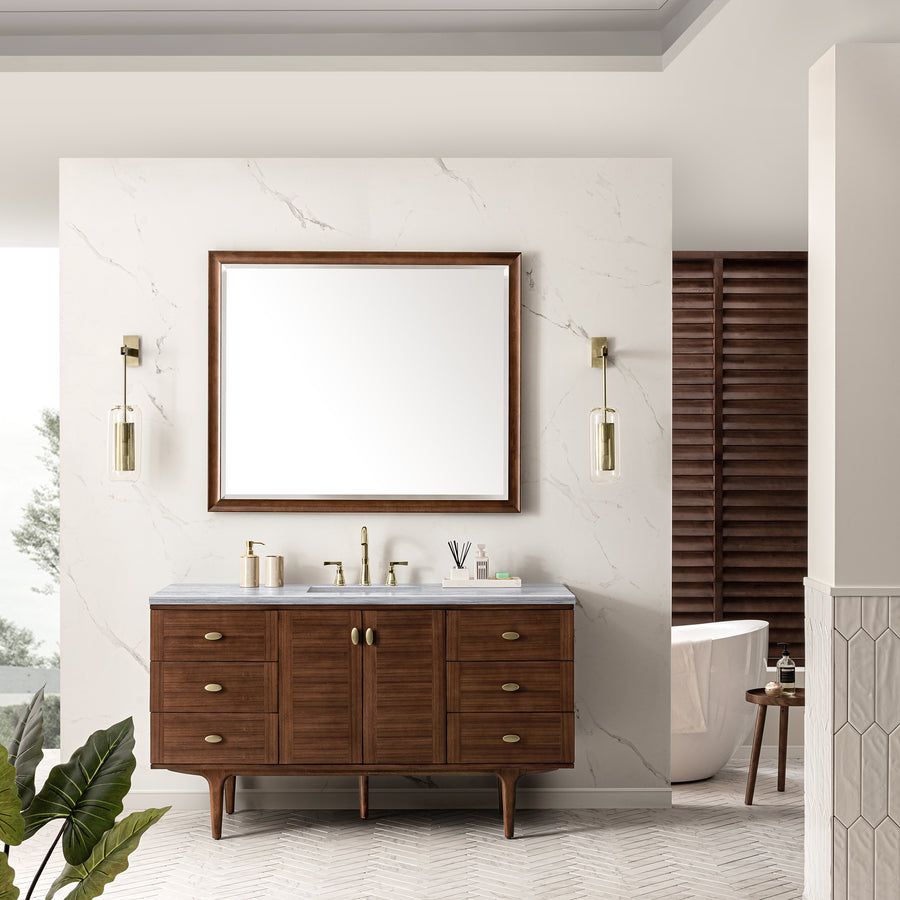 A modern bathroom features a large mirror above an Amberly 60" Vanity with walnut cabinet, marble wall, twin sconces, gold fixtures, white freestanding tub, and a green plant accenting the Mid-Century Modern design.