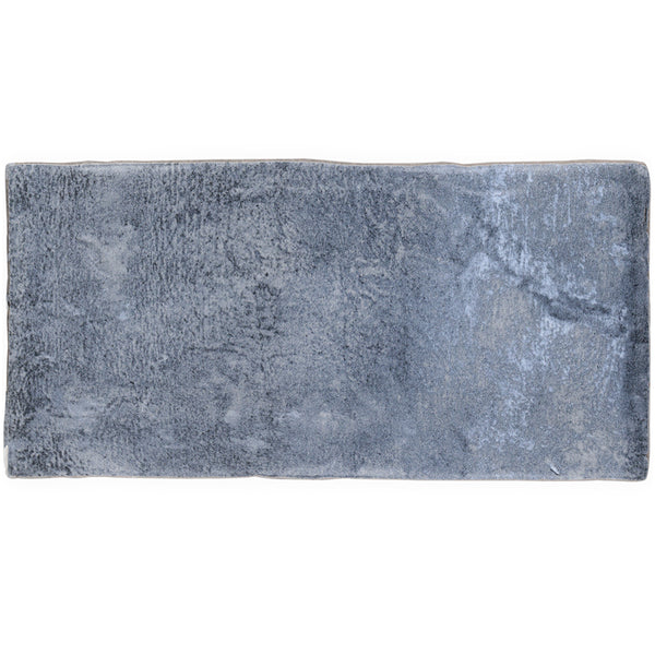 The Morocco 4x8 White Body Ceramic Tile features a rectangular shape and matte finish with subtle texture, evoking rustic charm in gray-blue tones, and is displayed from above against a white background.