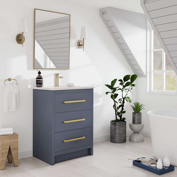 A modern bathroom with a blue vanity, gold hardware, a rectangular mirror, two white sconces, potted plants, a towel ring, and a white bathtub by a sunny window. Light wood floor and angled white plank ceiling.