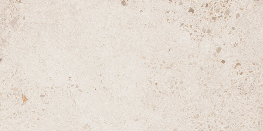 The Strata 12" x 24" Tile in Lava White features a light beige surface with small gray and brown specks, offering a subtle textured look ideal for contemporary bathrooms and mimicking the appearance of natural terrazzo or concrete.