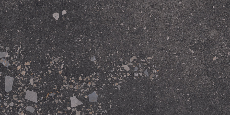 Close-up of Strata 12" x 24" Tile in Ember Rectified, featuring a rough, dark concrete look with textured light and dark stone fragments for a durable, contemporary finish.