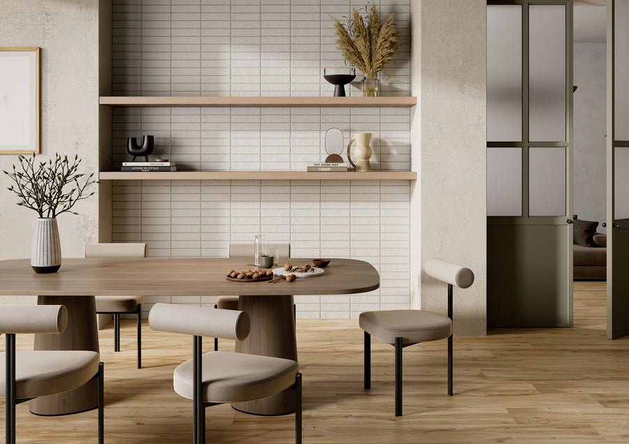 A modern dining area with a wooden table, four cushioned chairs, and minimalist decor. Shelves with vases and dried plants are mounted on a tiled wall. Light wood flooring and neutral tones create a calm atmosphere.