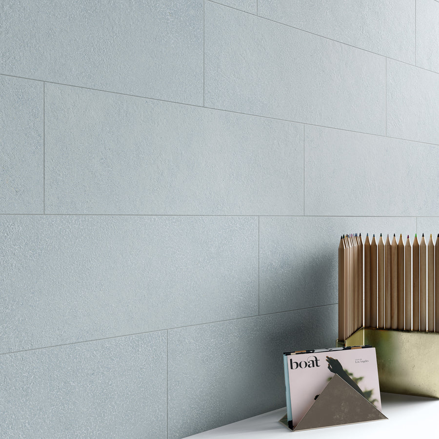 A light blue textured tiled wall with a white surface in front, holding a magazine titled boat and a gold geometric organizer filled with vertical files.