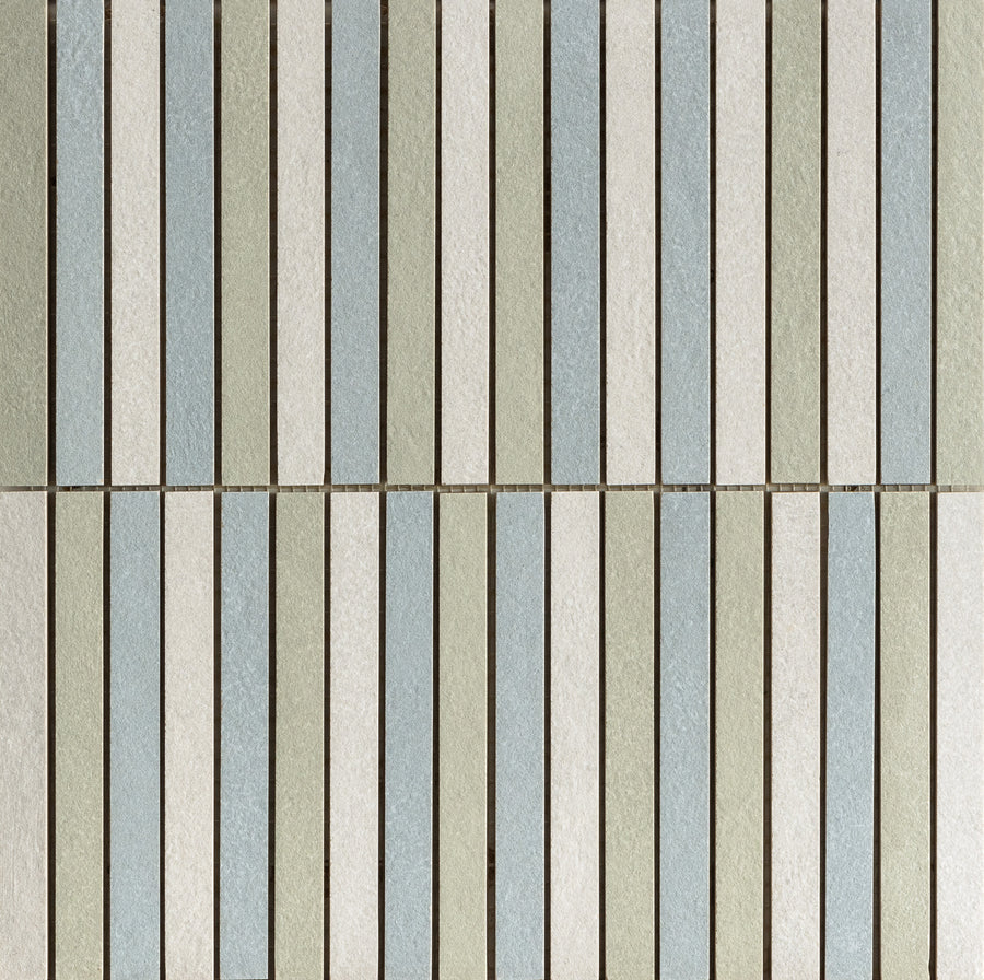 A tile wall features Avanti Straight Stack Mix Glazed Porcelain Tile in vertical rectangles, alternating pastel blue, gray, and green shades with thin brown grout lines for a symmetrical, calming look.
