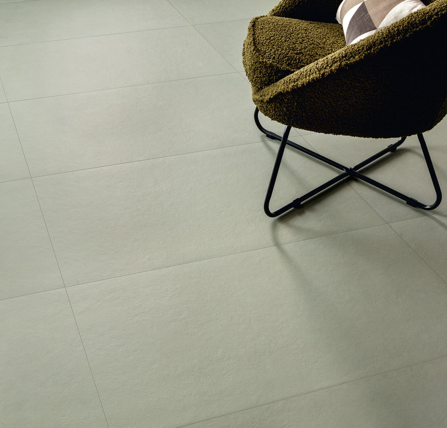 A textured light gray tiled floor with a modern chair featuring dark metal legs and a brown upholstered seat, partially shown in the upper right corner.
