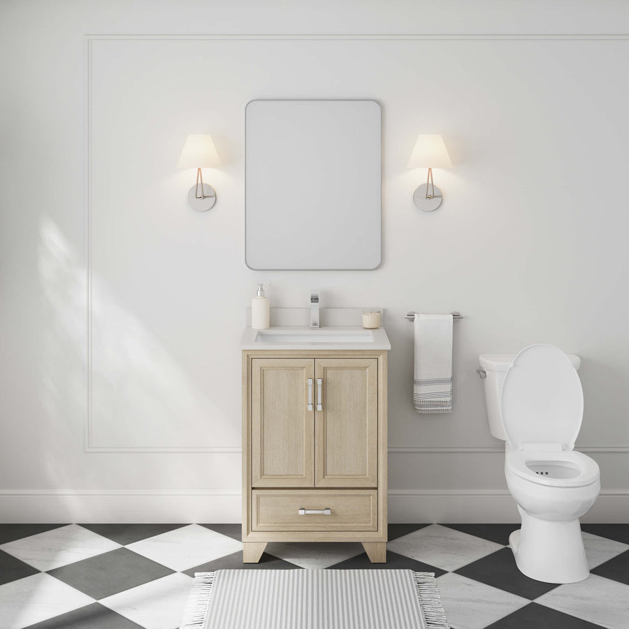 A minimal bathroom with the Ashlow 24" Vanity (engineered stone top, wood finish), rectangular mirror, two wall sconces, white toilet, towel rack, checkered floor tiles, and striped rug lit by natural light from the left.