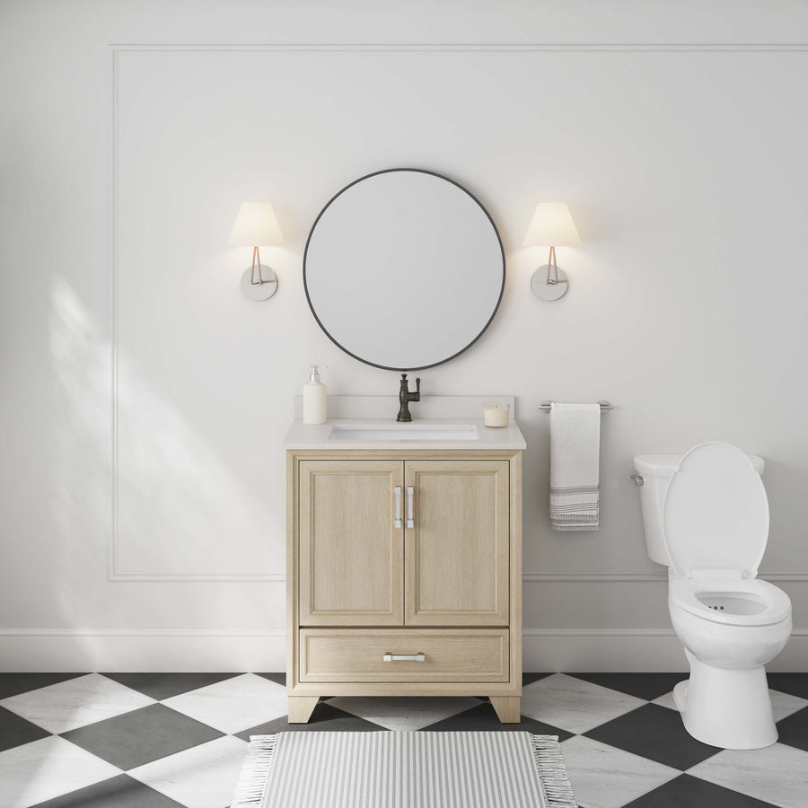 A modern bathroom with an Ashlow 30" w/ Engineered Stone Top Vanity, round mirror, two wall sconces, white toilet, towel, checkered black-and-white tile floor, and a white paneled wall.