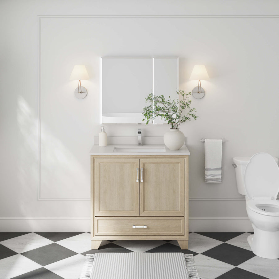 A bright, modern bathroom showcases the Ashlow 36" Vanity with an engineered stone top, a square mirror, wall sconces, a potted plant, and a white toilet. Black and white checkered floor tiles are accented by a striped rug in front of the vanity.