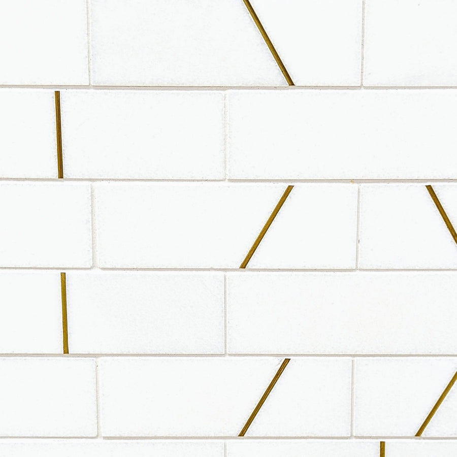 Abstract 2x6 Polished Marble Mosaic Tile features white rectangular tiles in a brick pattern, accented by thin diagonal gold lines on select pieces, creating a sleek and modern look ideal for contemporary interiors.