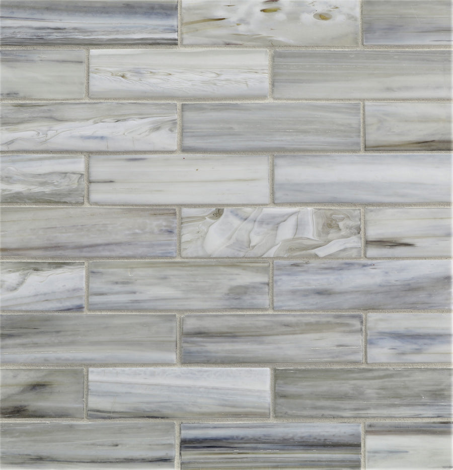 Agate 1 1/4" x 5" Bari Mosaic Glass Tile features rectangular glass tiles in white, gray, and light blue with marbled streaks and elegant variations, arranged in a brick-like pattern for a refined look.