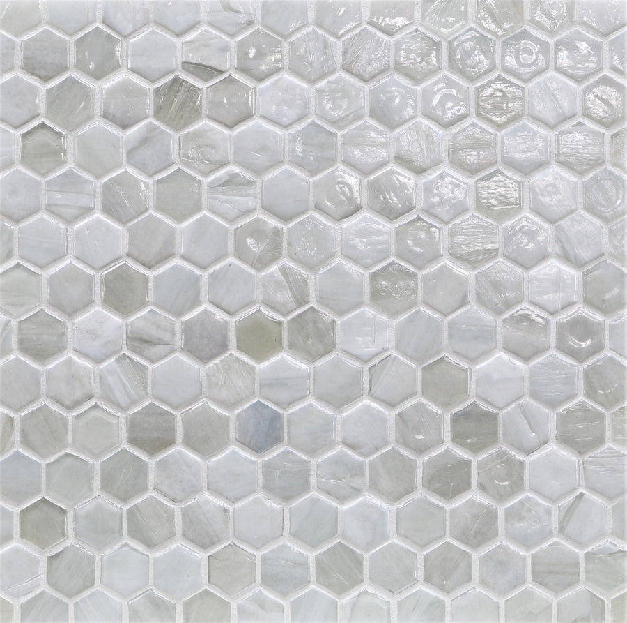 Close-up of a wall or floor featuring Agate Hexagon Mosaic Glass Tile—small hexagonal glass tiles in light gray and white shades with a glossy finish, arranged evenly in a honeycomb pattern.