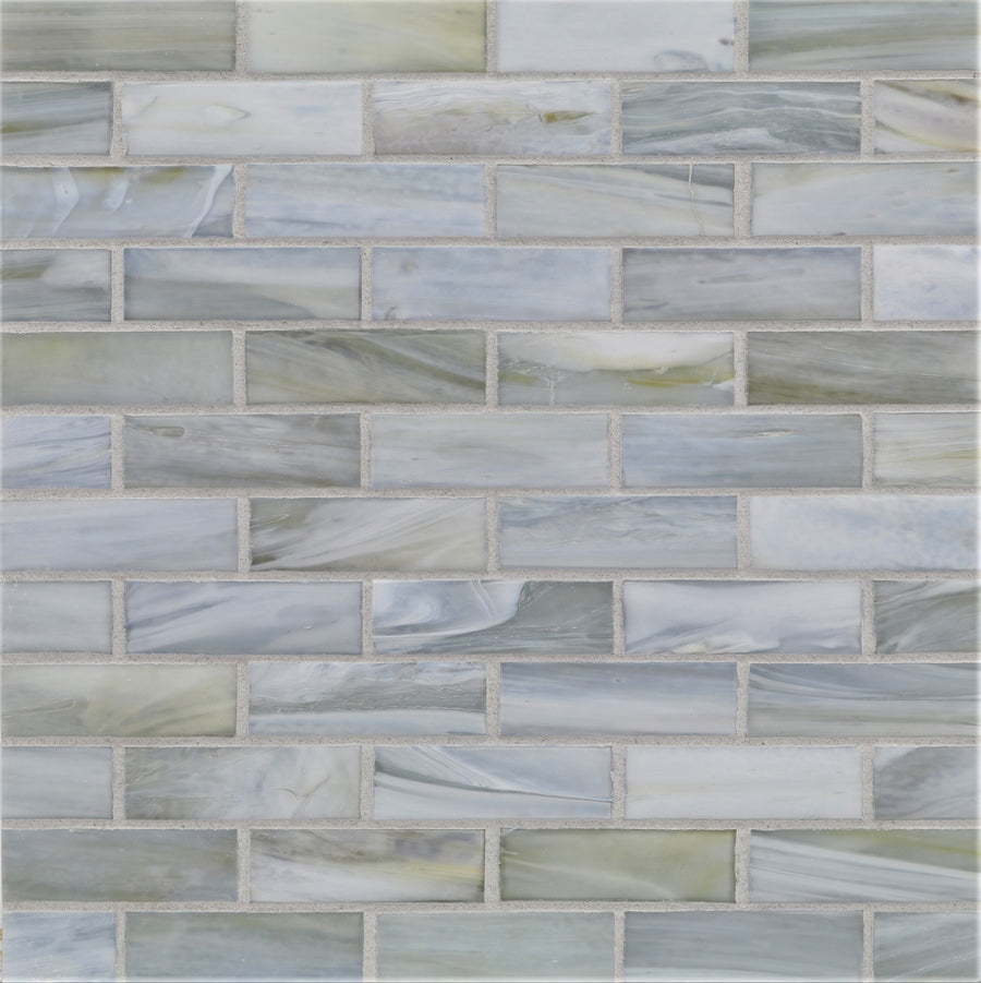 The Agate 1x3 Lucca Mosaic Glass Tile features glossy rectangular pieces in gray, blue, and white with a marbled texture and subtle color variation, arranged in a staggered brick pattern with light gray grout for a modern look.