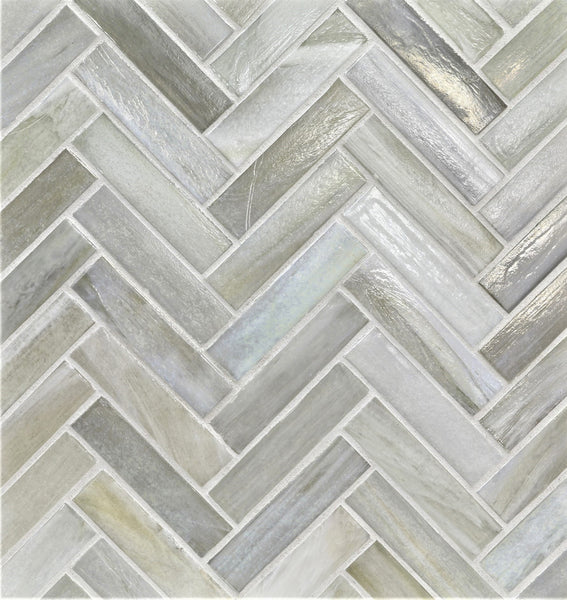 The Agate 1x4 Herringbone Asolo Mosaic Glass Tile features light grey and white pieces in a geometric pattern with subtle color variation and a glossy finish, creating a modern, textured look.