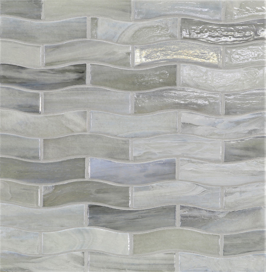 A close-up of the Agate Zing Torino Mosaic Glass Tile shows wavy, rectangular glass tiles in gray and white tones, forming a fluid, three-dimensional pattern with a glossy finish.
