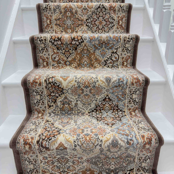 The Ancient Garden 57008-9696 Runner Rug, featuring intricate beige, brown, and blue floral patterns, is centered on a white-painted staircase for a traditional and elegant look.