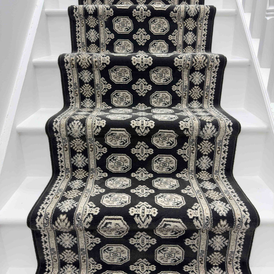 A staircase featuring the Ancient Garden 57102-3636 Runner Rug with black and white geometric and floral patterns, bordered by white-painted steps—an eye-catching option for a hallway or entryway rug.