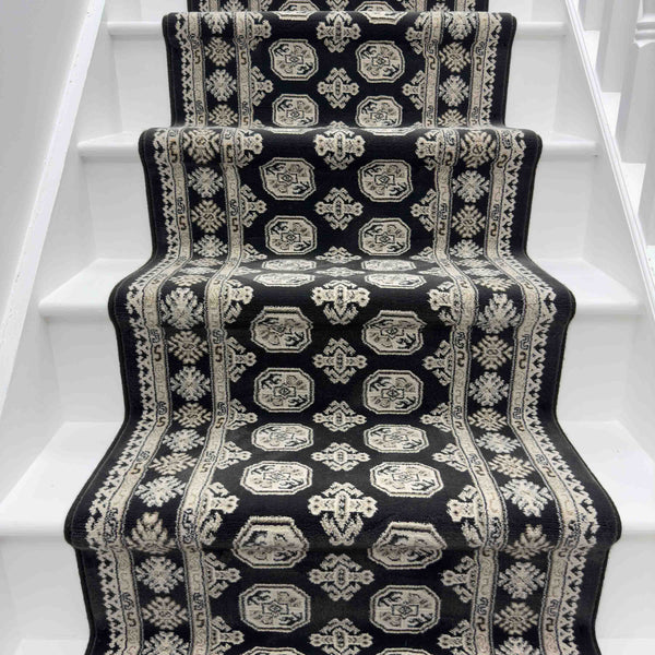 A staircase featuring the Ancient Garden 57102-3636 Runner Rug with black and white geometric and floral patterns, bordered by white-painted steps—an eye-catching option for a hallway or entryway rug.