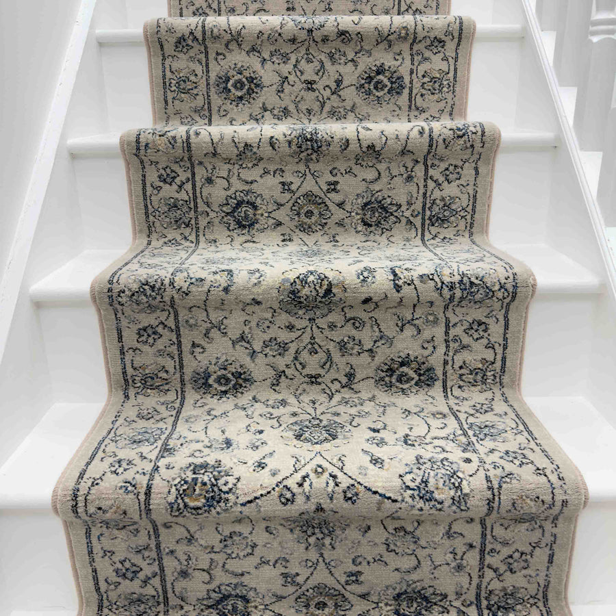 A white staircase paired with the Ancient Garden 57126-6666 Runner Rug creates an elegant hallway look.