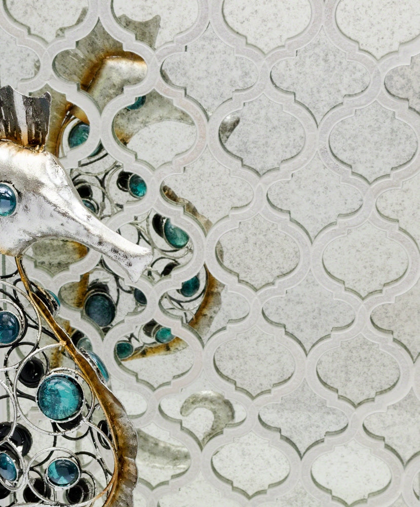 A decorative metallic seahorse with turquoise accents is positioned against a patterned, reflective background, creating mirrored reflections and a textured, artistic effect.