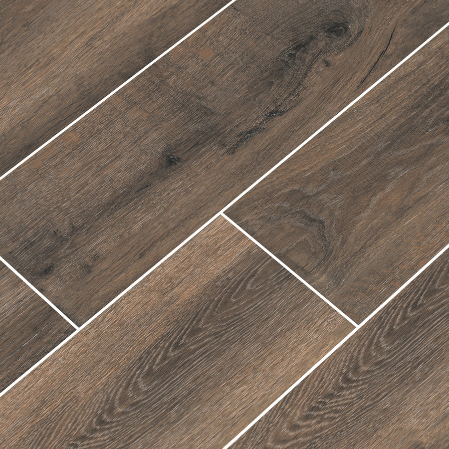 Close-up view of brown wood-look floor tiles arranged in an offset pattern, with visible wood grain texture and light-colored grout lines separating each tile.