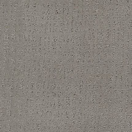 A close-up of the Homage Berber Carpet in Art Deco highlights its textured gray surface with a subtle, irregular grid pattern—slightly raised, darker threads add depth, making it a durable and timeless option for high-traffic spaces.
