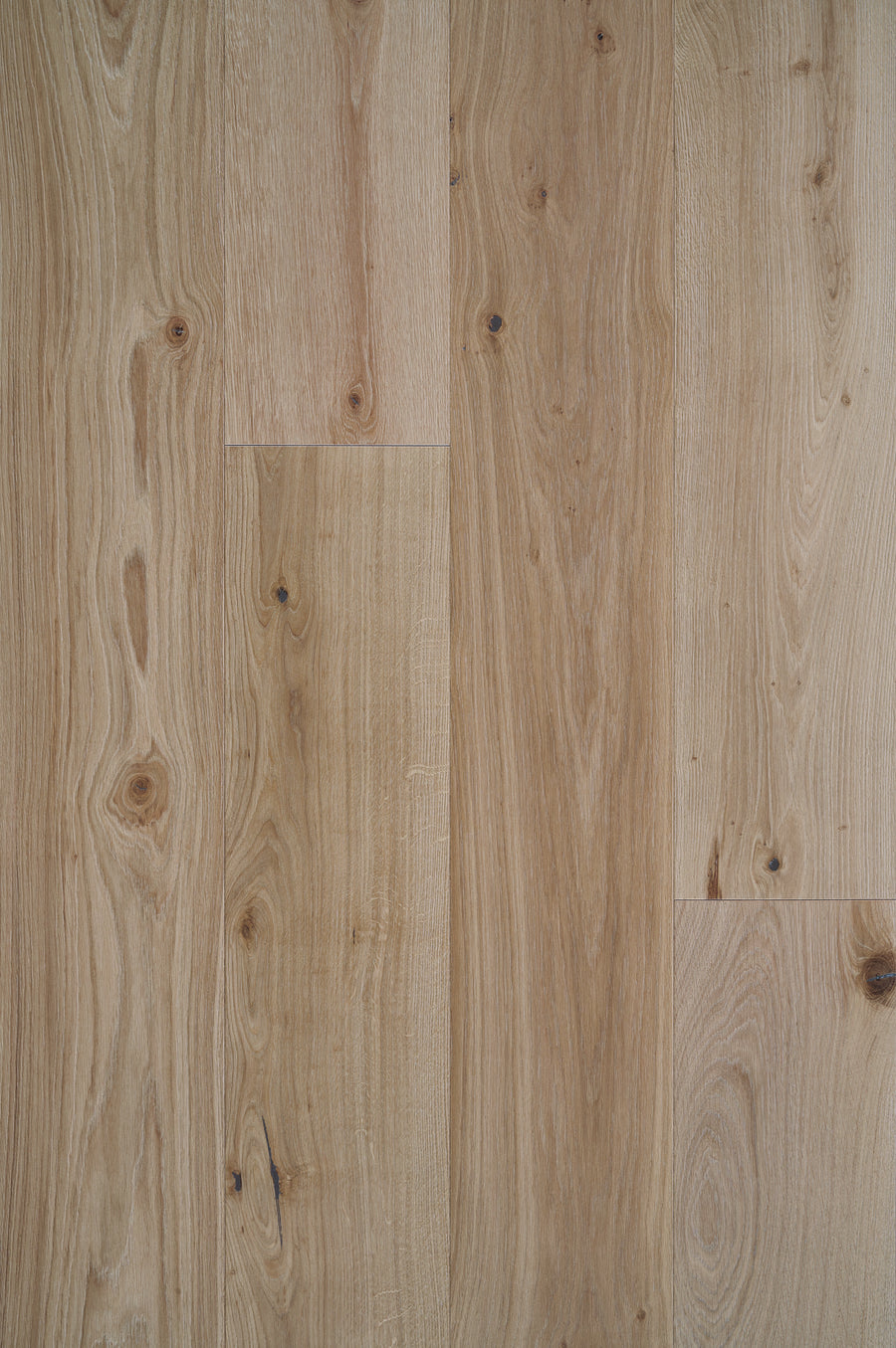 Close-up of Tribeca Loft French Oak 9.4" Hardwood in Astoria, featuring natural brown tones with wood grain and knots, planks arranged vertically side by side.