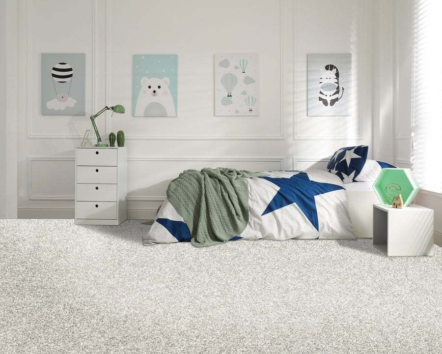 A modern childrens bedroom with white walls, a single bed with star-patterned bedding, a green throw, a white nightstand with a green lamp, and three animal-themed pictures hanging above the bed.