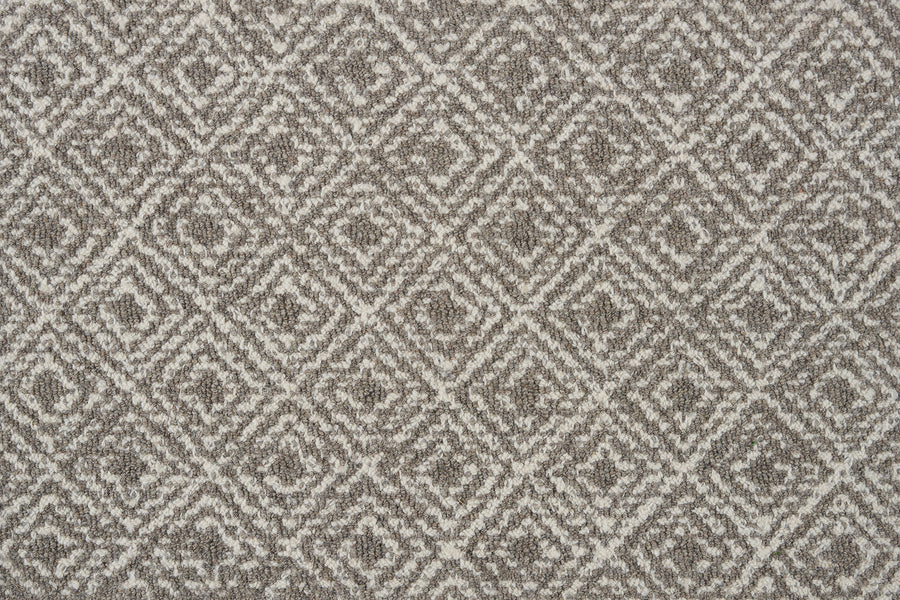 Close-up of Brentwood Berber Carpet in Flannel, showcasing its textured fabric with a repeating diamond pattern in gray and white for a sophisticated, geometric, and symmetrical look.