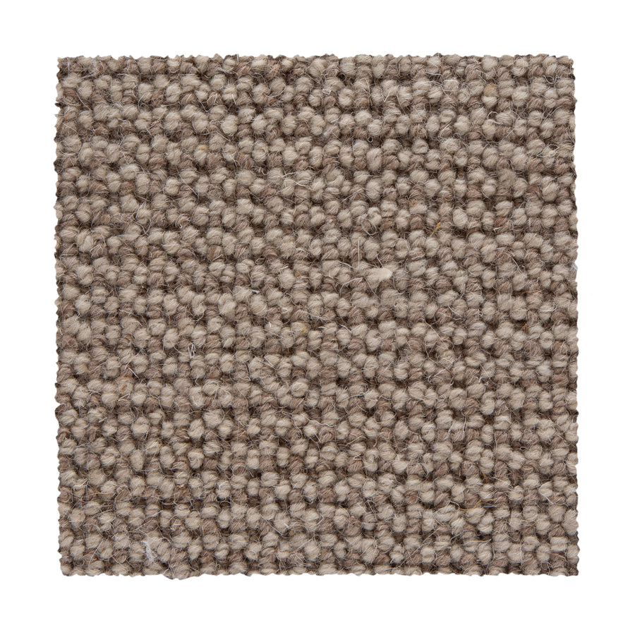 A close-up of a Bellarine Berber Carpet swatch in Cork shows its tightly looped, textured weave in beige and light brown tones, highlighting the carpet's durability and design against a white background.