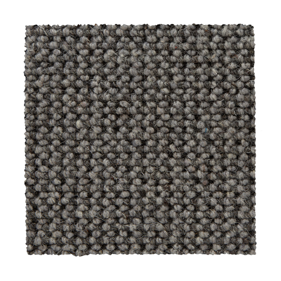 A square swatch of Bellarine Berber Carpet in Mindful Gray, featuring a loop-pile texture and tightly woven surface, is shown on a white background—highlighting this carpet's refined style and durability.