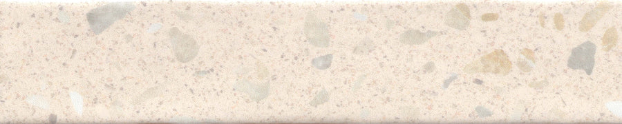 A close-up of Fragmento 2x10 Ceramic Tile in Bone Voyage shows a smooth beige surface with light brown, gray, and cream specks and patches. The subtle terrazzo-inspired pattern adds gentle visual interest to the ceramic tile.
