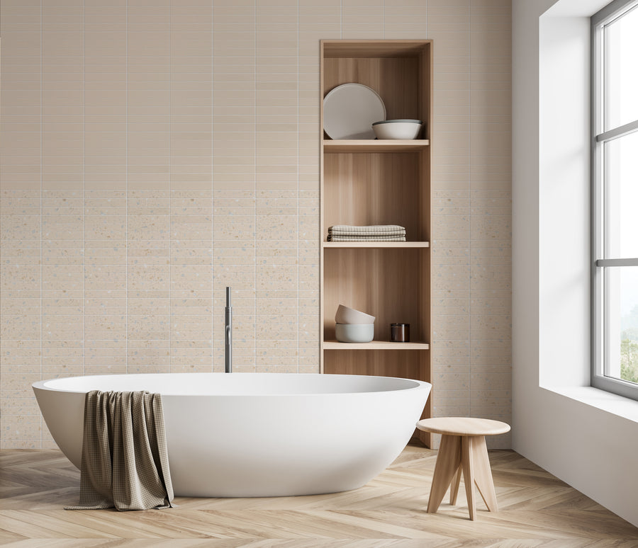 Minimalist bathroom with a white freestanding bathtub, a wooden stool, and an open shelving unit holding towels and dishes. Beige tiled walls and a large window provide natural light and a serene atmosphere. A towel hangs on the tub.
