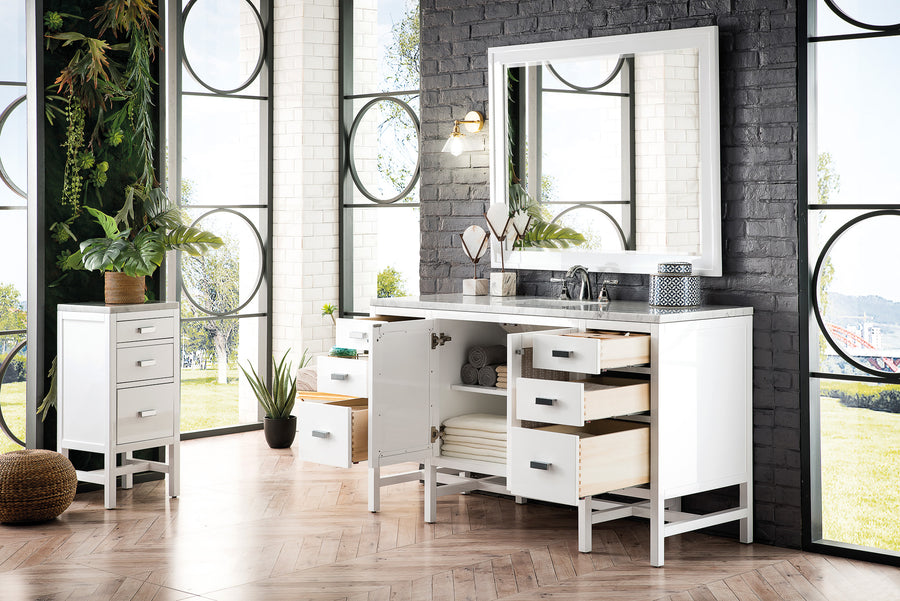Modern bathroom with white vanity and matching cabinet. Vanity drawers and doors are open, displaying storage space. Large mirror above, potted plants, and tall windows let in abundant natural light. Brick and tile walls complete the look.