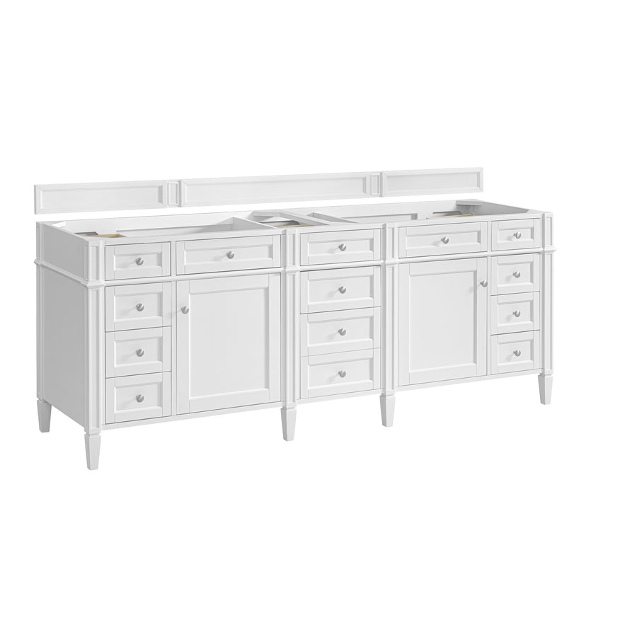 A large white double-sink bathroom vanity with multiple drawers and cabinets, featuring classic paneling and silver knobs, shown without countertops or sinks.