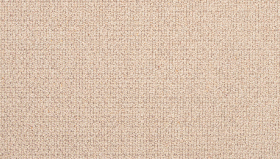 Close-up of the Brixham Berber Carpet in Sandbar, showing a tight, grid-like weave. The beige surface is soft and uniform, with subtle thread color variations for an elegant, luxurious appearance.