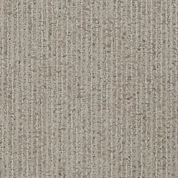 A close-up of Suspicion Family Friendly Carpet in Burnish shows its textured, stain resistant surface with vertical, slightly raised lines and a blend of fine and coarse fibers—ideal for family spaces.