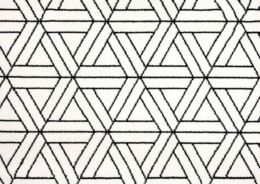The Black & White On Trend Carpet in Pure features a modern, durable design with interlocking hexagons and triangles forming a repeating, geometric black and white pattern.