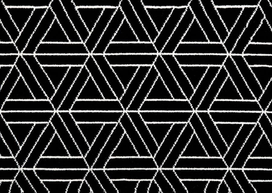 Ebony Black & White On Trend Carpet features a bold geometric pattern of interlocking white hexagons and triangles on a black background, creating a luxurious and modern statement for any space.