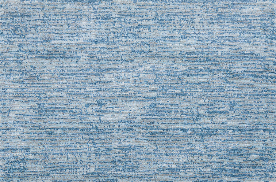 A close-up of the Olde Chatham On Trend Carpet in Sky shows its blue and light gray horizontal textured pattern, reflecting modern style and durable weave.