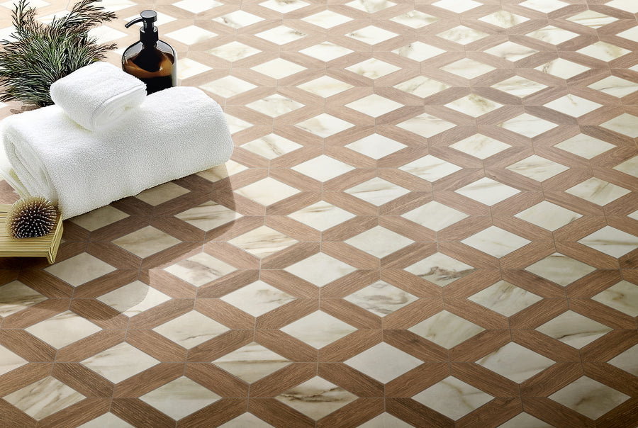 A close-up of a geometric-patterned floor with beige and white tiles, featuring a rolled white towel, a bottle with a pump, a scrub brush, and green plant sprigs arranged on the floor.