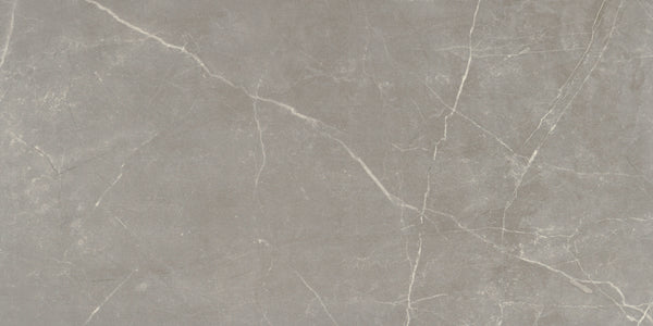 The Callie 12x24 Polished Porcelain Tile in Fog features a light gray surface with subtle white veining and natural-looking cracks, offering a textured, organic look that’s perfect for elegant interior spaces.