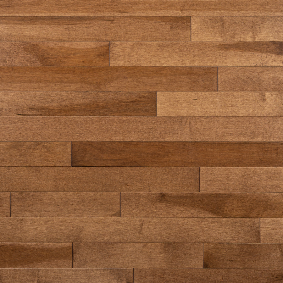 Close-up of Champlain Maple ¾" x 3 1/4" Hardwood planks in medium brown, laid horizontally to showcase natural wood grain and subtle color variations for a durable, dent-resistant flooring surface.