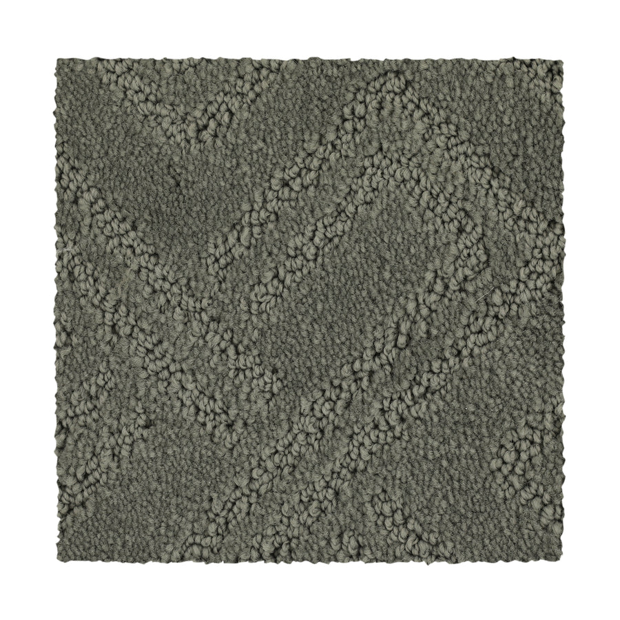 A square swatch of Classic Frame Family Friendly Carpet in Retreat. This dark gray luxury carpet features a raised zigzag pattern and a mix of looped and cut fibers, creating a subtle geometric design with clean edges for sophisticated appeal.