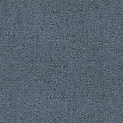 A close-up of the Homage Berber Carpet in Classico reveals a textured gray surface with a unique dotted pattern, offering durable performance and an appealing look—perfect for high-traffic areas.