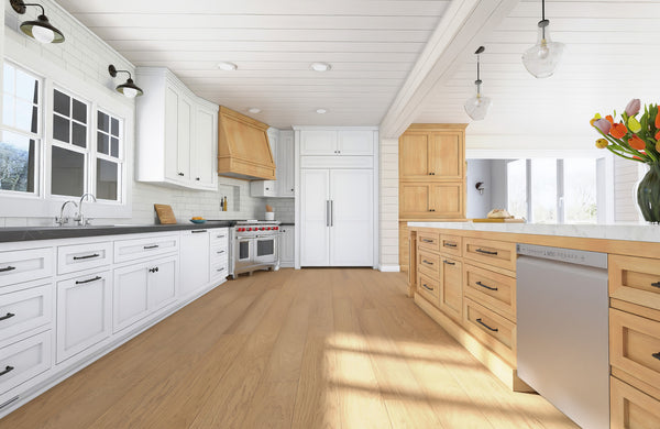A spacious, modern kitchen with white and light wood cabinets, a large island with a dishwasher, stainless steel appliances, pendant lights, flowers in a vase, and ample natural light from tall windows.